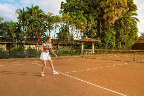 a woman holding a tennis racket on a tennis court at Tequendama Hotel Campestre Villavicencio in Villavicencio