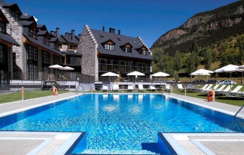 una gran piscina azul frente a un edificio en Apartamentos HG Cerler, en Cerler