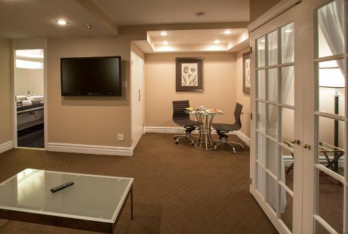 a living room with a tv and a table and chairs at Hôtel Le Cantlie Suites in Montréal