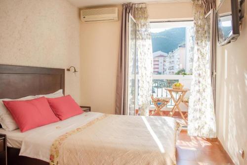 a bedroom with a bed with red pillows and a window at Hotel Villa Perla Di Mare in Budva