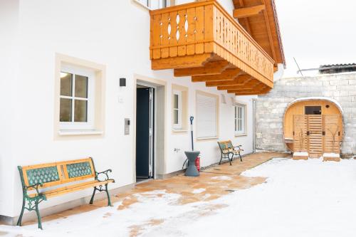 a patio with two benches and a balcony at LIBORIA I Traumhafte Ferienwohnung in Aidling am Riegsee in Riegsee
