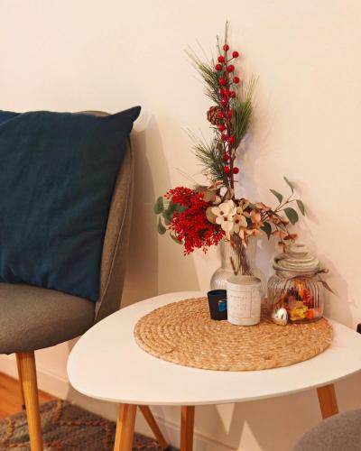 a table with a vase with flowers on it next to a chair at Azulejo Apartment in Novi Beograd