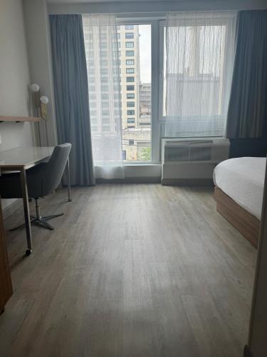 a hotel room with a bed and a desk and window at TownePlace Suites by Marriott New York Long Island City in Queens
