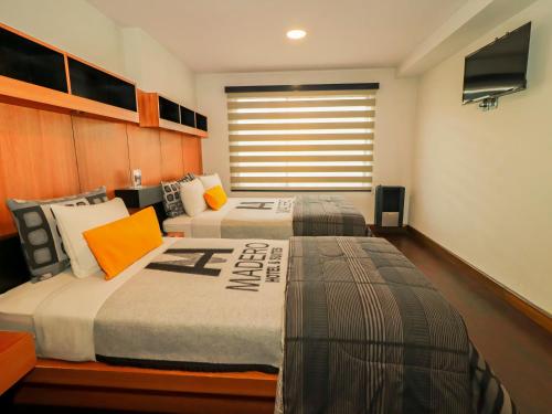 a bedroom with two beds and a flat screen tv at Madero Hotel & Suites in La Paz