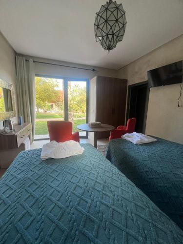 a hotel room with two beds and a table and chairs at RIAD REDWAN in Marrakech