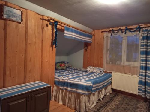 a bedroom with a bed in a room with wooden walls at Gostynnyi Dvir u Marichky in Lazeshchyna