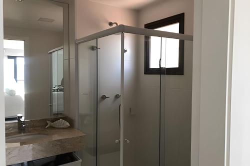 a bathroom with a glass shower and a sink at Arraial | Apartamento com 3 suítes e Vista Mar in Arraial do Cabo