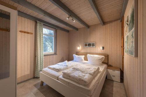 a bedroom with a bed with white sheets and a window at Wildgans 65 in Mirow