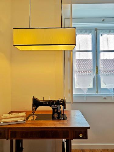 a sewing machine sitting on a table next to a window at The Fabric - 2BR apt in Lisbon