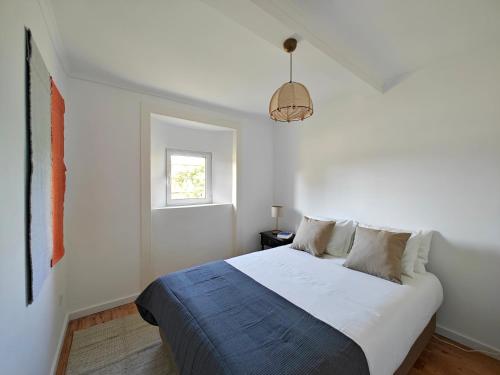 a white bedroom with a bed and a window at The Fabric - 2BR apt in Lisbon