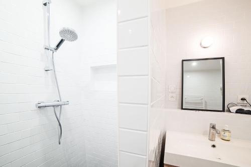 une salle de bain blanche avec une douche et un lavabo dans l'établissement large pleasant studio alcove in center, à Paris