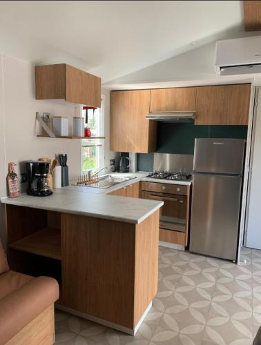 une cuisine avec des armoires en bois et des appareils en acier inoxydable dans l'établissement Cb - Espace & confort, 3 ch, 41m2, proche mer, à Lattes