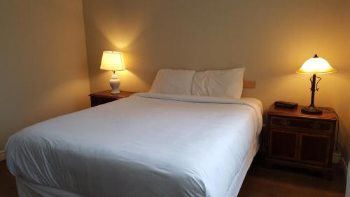 um quarto com uma grande cama branca e 2 candeeiros em Duvernay Studios and Suites em Gatineau