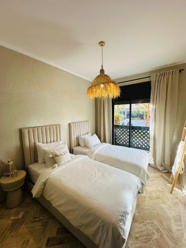 a bedroom with two beds and a chandelier at Dar Celya Sfia in Marrakech