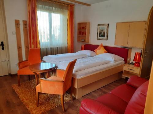 a bedroom with a bed and a table and a couch at Hotel Restaurant Kirchsteiger in Vollan