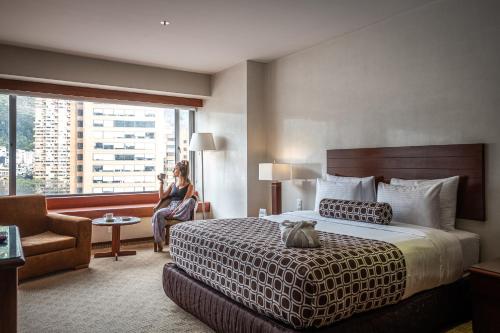 a woman in a hotel room with a bed and a window at Tequendama Suites Bogota in Bogotá
