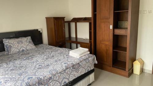 a bedroom with a bed and a wooden cabinet at Griya Kania Merapi in Sleman