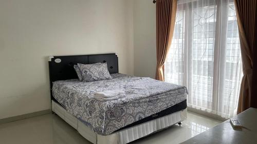 a bedroom with a bed and a large window at Griya Kania Merapi in Sleman