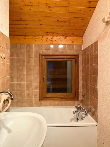 une salle de bain avec une baignoire, un lavabo et un miroir dans l'établissement Au cœur des pistes, à Saint-Gervais-les-Bains