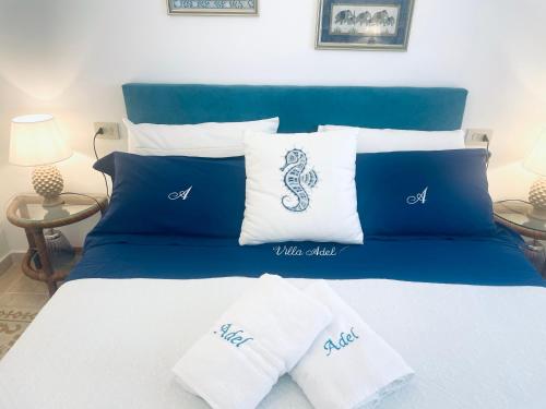 een bed met blauwe en witte kussens erop bij Villa Adel in San Teodoro