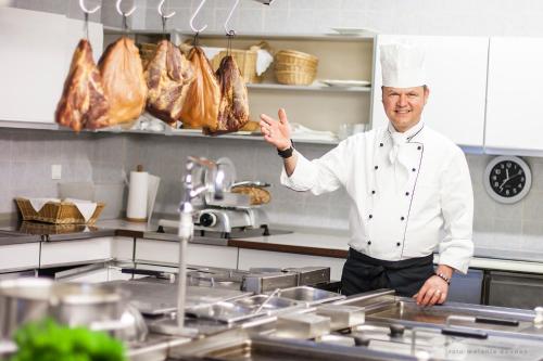 a chef standing in a kitchen with some meat at Hotel-Restaurant-Haus Berger in Viersen