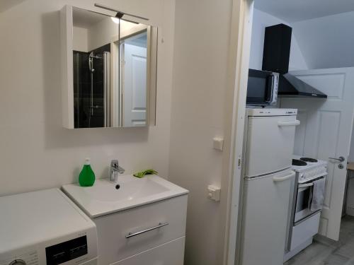 a white bathroom with a sink and a mirror at Central Apartament in Tromsø