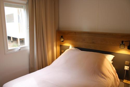 a bedroom with a white bed with a window at Mobilhome Les Embruns by Siblu in Lège-Cap-Ferret