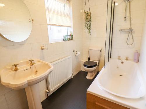 a bathroom with a sink and a toilet and a tub at Lavender Cottage in Louth