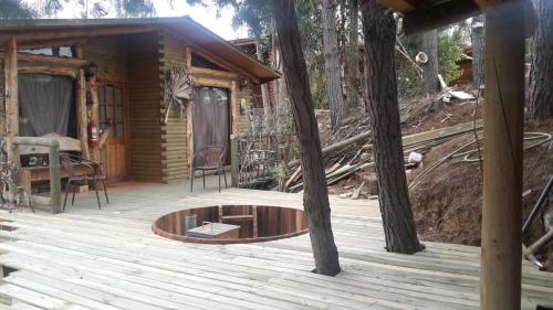 a cabin with a wooden deck with a fire pit at Cabañas Rukas Licantén in Licantén