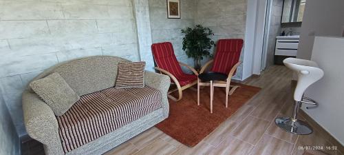 a living room with a couch and two red chairs at Bella vista Šumarice in Kragujevac