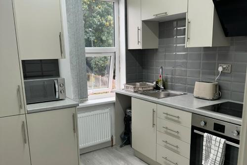 a kitchen with white cabinets and a sink and a window at City Chic Retreat In Birmingham in Birmingham