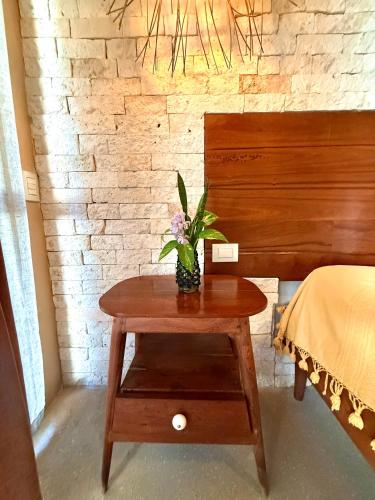 a table with a vase of flowers on it next to a bed at XscapeTulum in Tulum