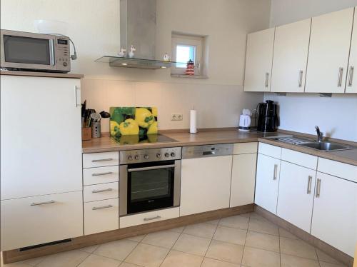 a kitchen with white cabinets and a microwave at Villa Seeperle - Seeschwalbe in Dahme