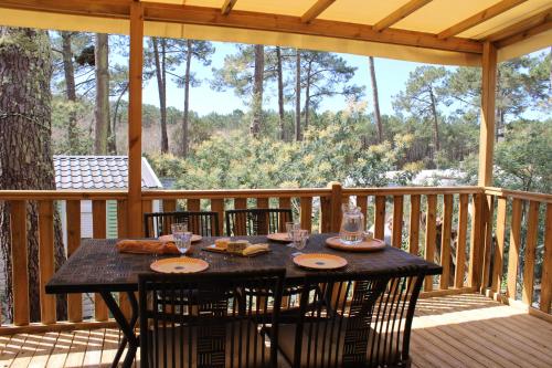 une terrasse en bois avec une table et des chaises. dans l'établissement Mobilhome Les Embruns by Siblu, à Lège-Cap-Ferret