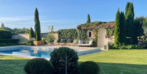 un jardin avec une piscine et une maison dans l'établissement Manoir de famille Beausoleil, à Allonnes
