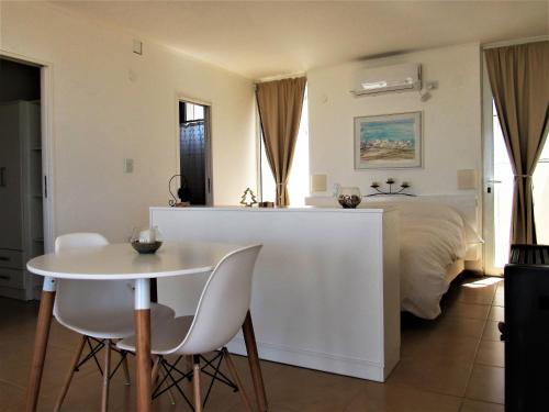 ein weißes Schlafzimmer mit einem Bett und einem Tisch und Stühlen in der Unterkunft Médanos Patagonia in Las Grutas
