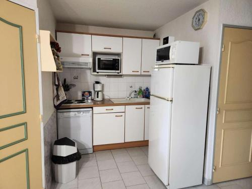 une cuisine avec des armoires blanches et un réfrigérateur blanc dans l'établissement Résidence Mimosas - Appartement T3 de 5 couchages dans un domaine arboré de la Coudoulière MAE-4521, à Six-Fours-les-Plages