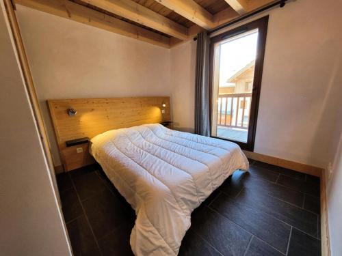 ein Schlafzimmer mit einem Bett mit einem großen Fenster in der Unterkunft Résidence Le Criterium - Résidence Le Critérium 3Chalet E Appartement 8 MAE-7751 in Lanslebourg-Mont-Cenis