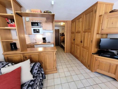 Elle comprend une petite cuisine avec des placards en bois et une télévision. dans l'établissement Résidence Le Soliet I - Studio pour 4 Personnes MAE-7821, à Bessans