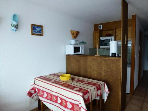 a kitchen with a table and a counter with a microwave at Résidence Les Balcons Des Curtious - Studio pour 4 Personnes MAE-7831 in Bessans