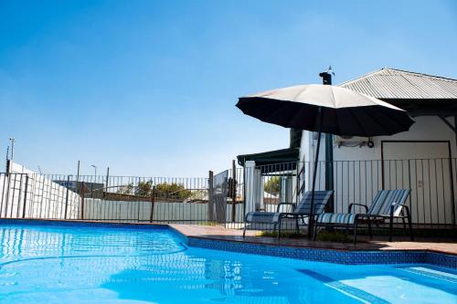 Una piscina con una sombrilla y dos sillas y una mesa y una sombrilla. en Unleashed guesthouse, en Johannesburgo