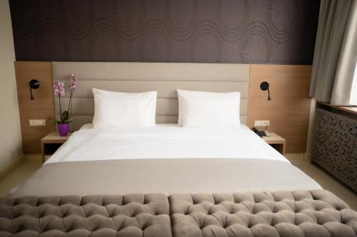 a large bed with white sheets and pillows at Hotel Srbija Garden-FREE PARKING in Belgrade