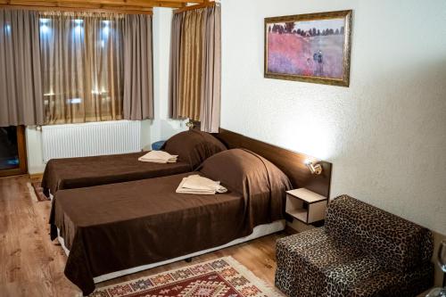 a hotel room with two beds and a chair at Matsurev Han in Bansko