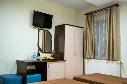 a hotel room with a desk and a tv on the wall at Matsurev Han in Bansko