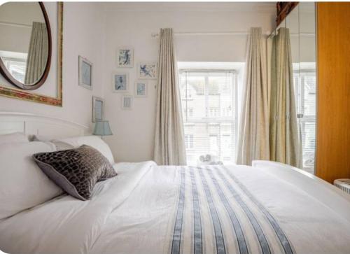1 dormitorio con cama blanca, espejo y ventana en Seahorse, en Dartmouth