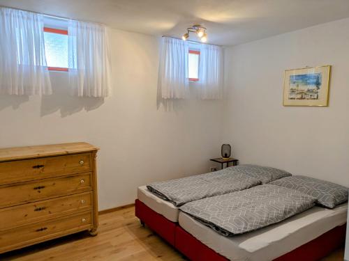 a bedroom with a bed and a dresser and windows at Appartments am Literaturbrunnen in Hartmannsdorf