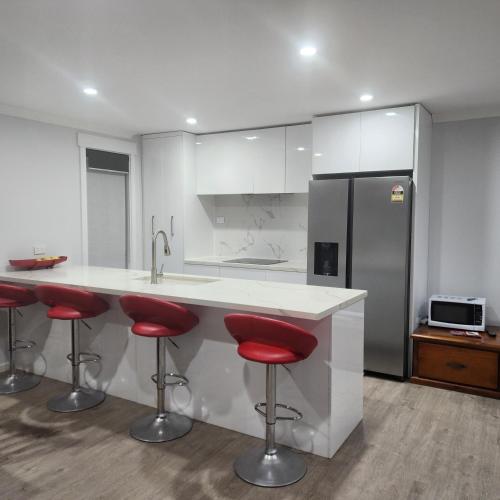 a kitchen with red bar stools and a refrigerator at CIA Home Stay Bendigo in Epsom
