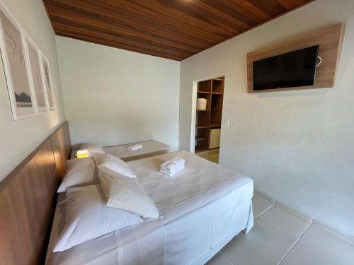 a small bedroom with a white bed and a flat screen tv at Hotel Roma in São Sebastião