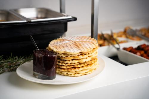 a stack of crackers on a plate with a drink at Hotel Srbija Garden-FREE PARKING in Belgrade