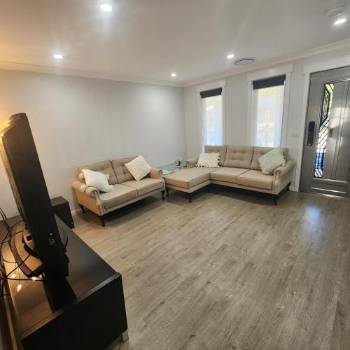 a living room with two couches and a flat screen tv at CIA Home Stay Bendigo in Epsom